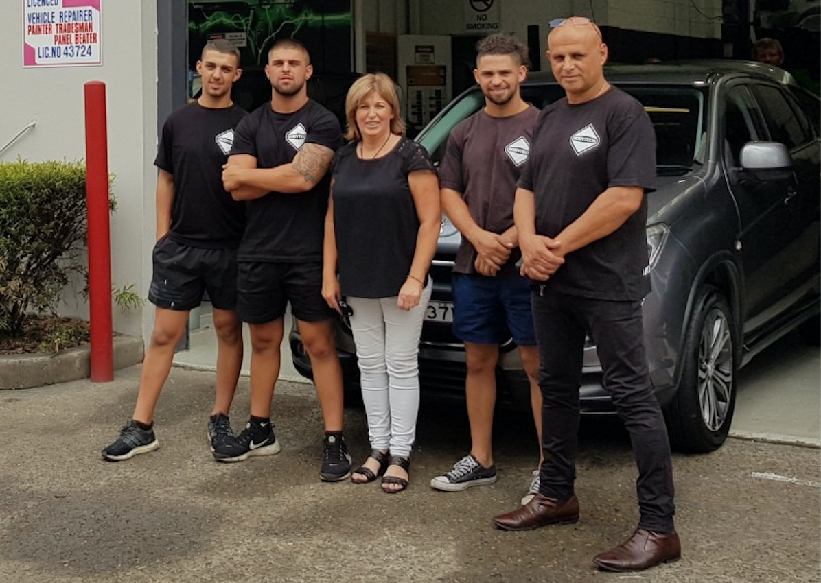 Auto body shop team in front of car in shop