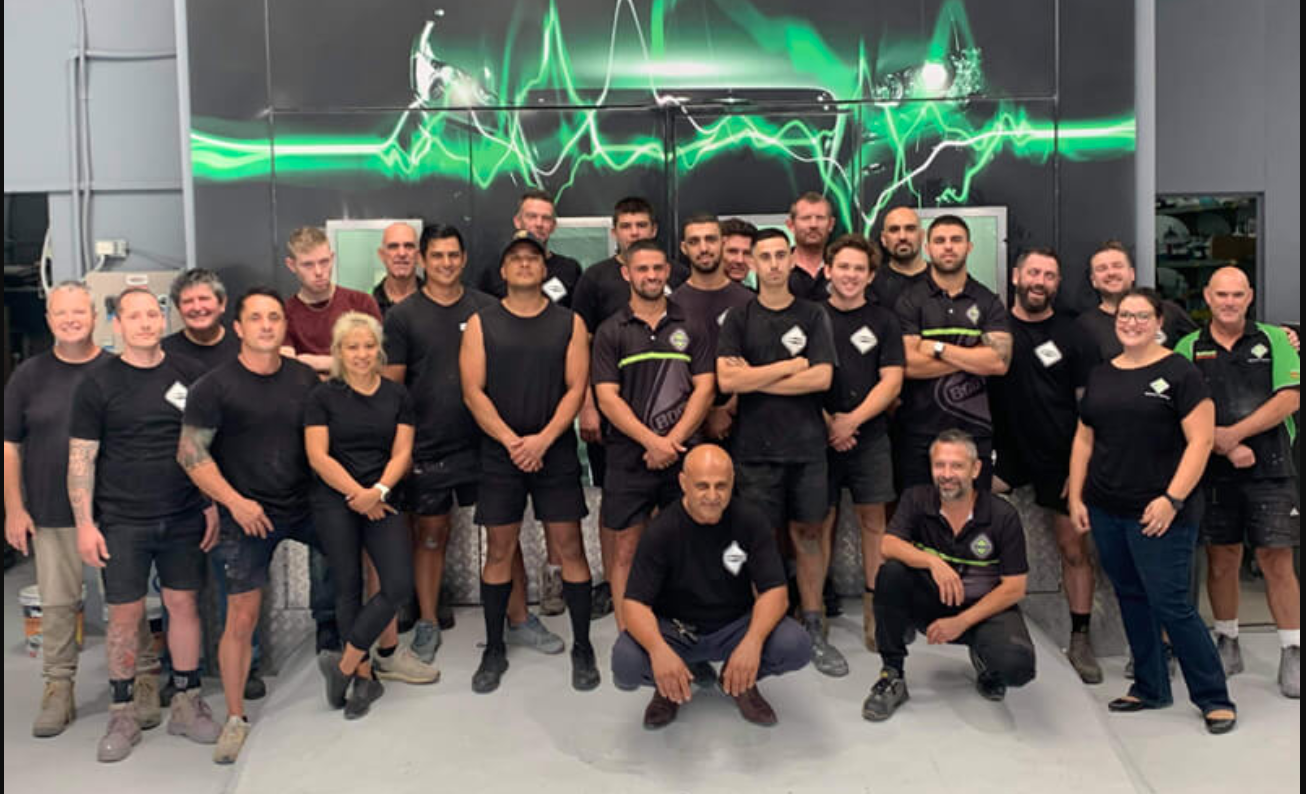 Whole team photo in front of wall art at Bodytech