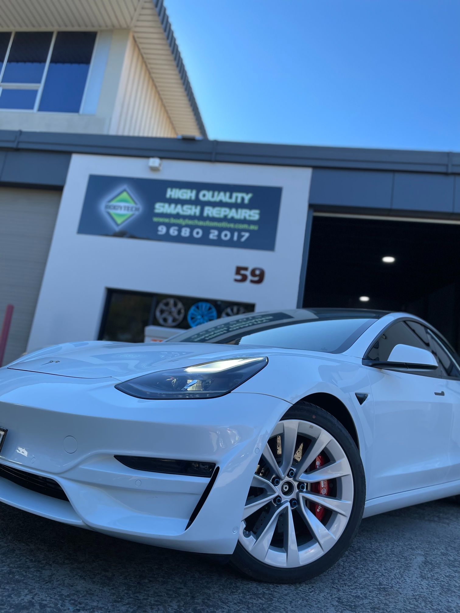 Detailed and spray painted Tesla in front of Bodytech Automotive garage